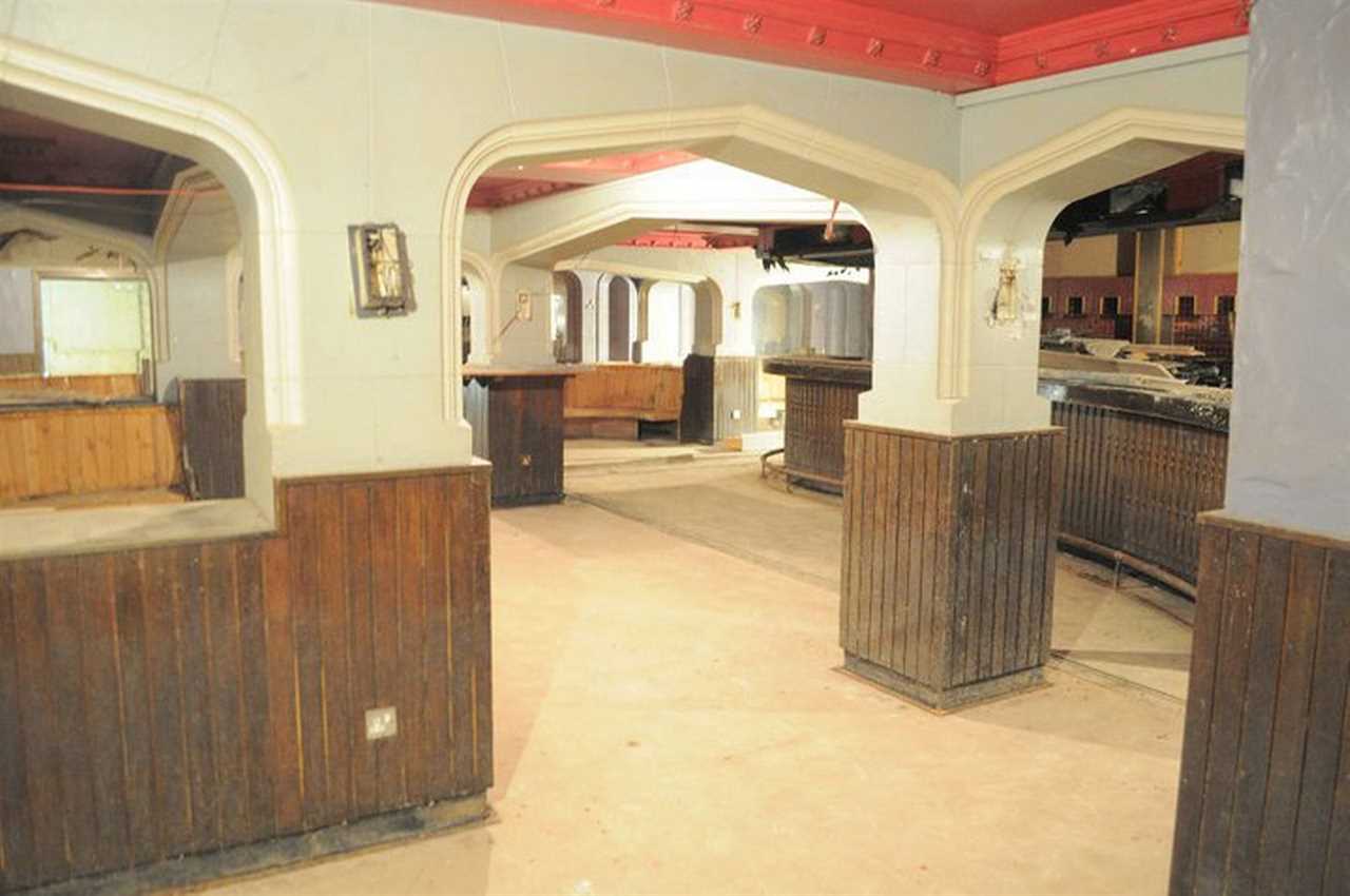 Inside pub frozen in time with empty pint glasses and bag of peanutstrapped underneath busy shopping centre