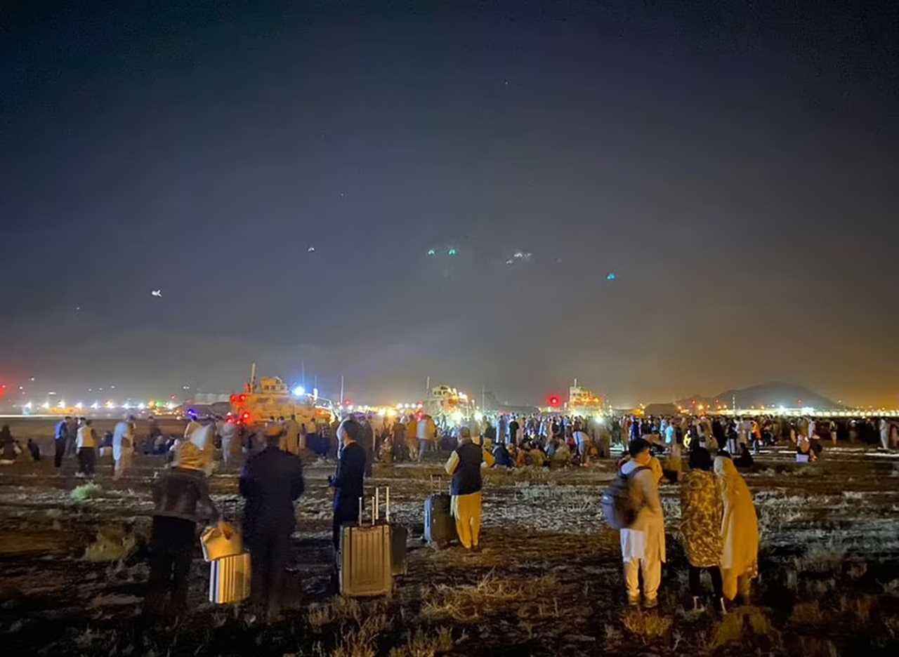 People waiting with suitcases near Kabul Airport's runway