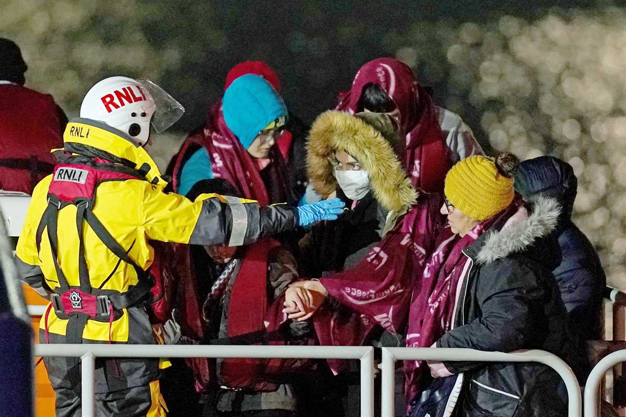 Migrants are led ashore in Dover this morning by RNLI rescuers