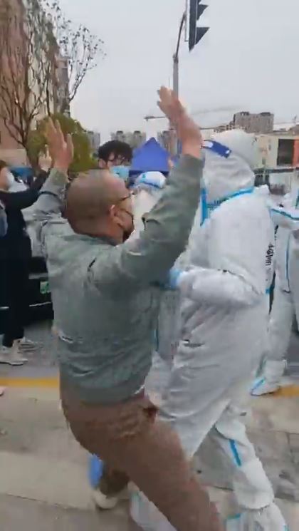 A man is seen with his arms raised before being led away by cops