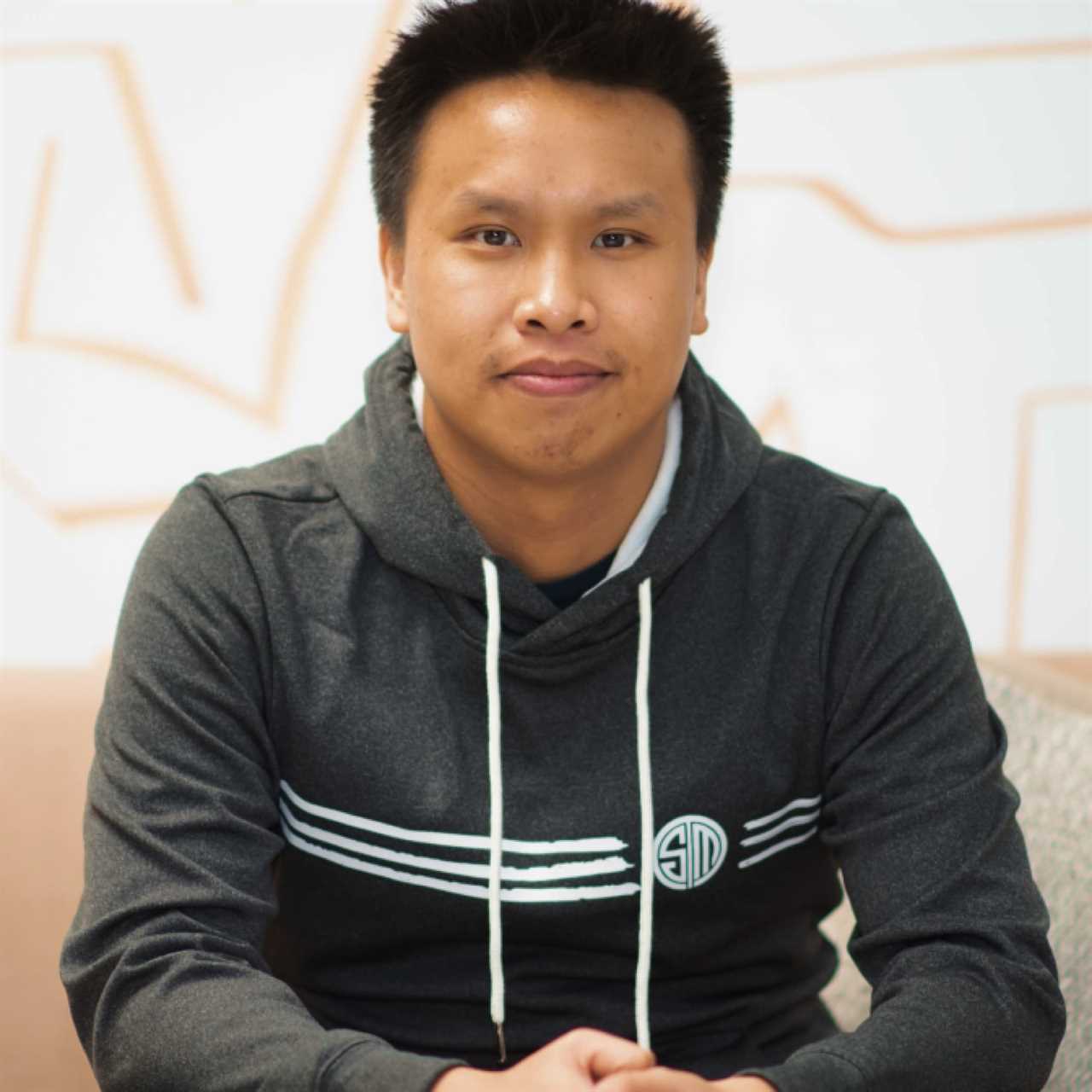 Andy Dinh sat hands clasped in a TSM hoodie. He is facing the camera.