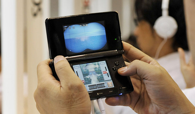 A man is holding a 3DS and is playing a game.