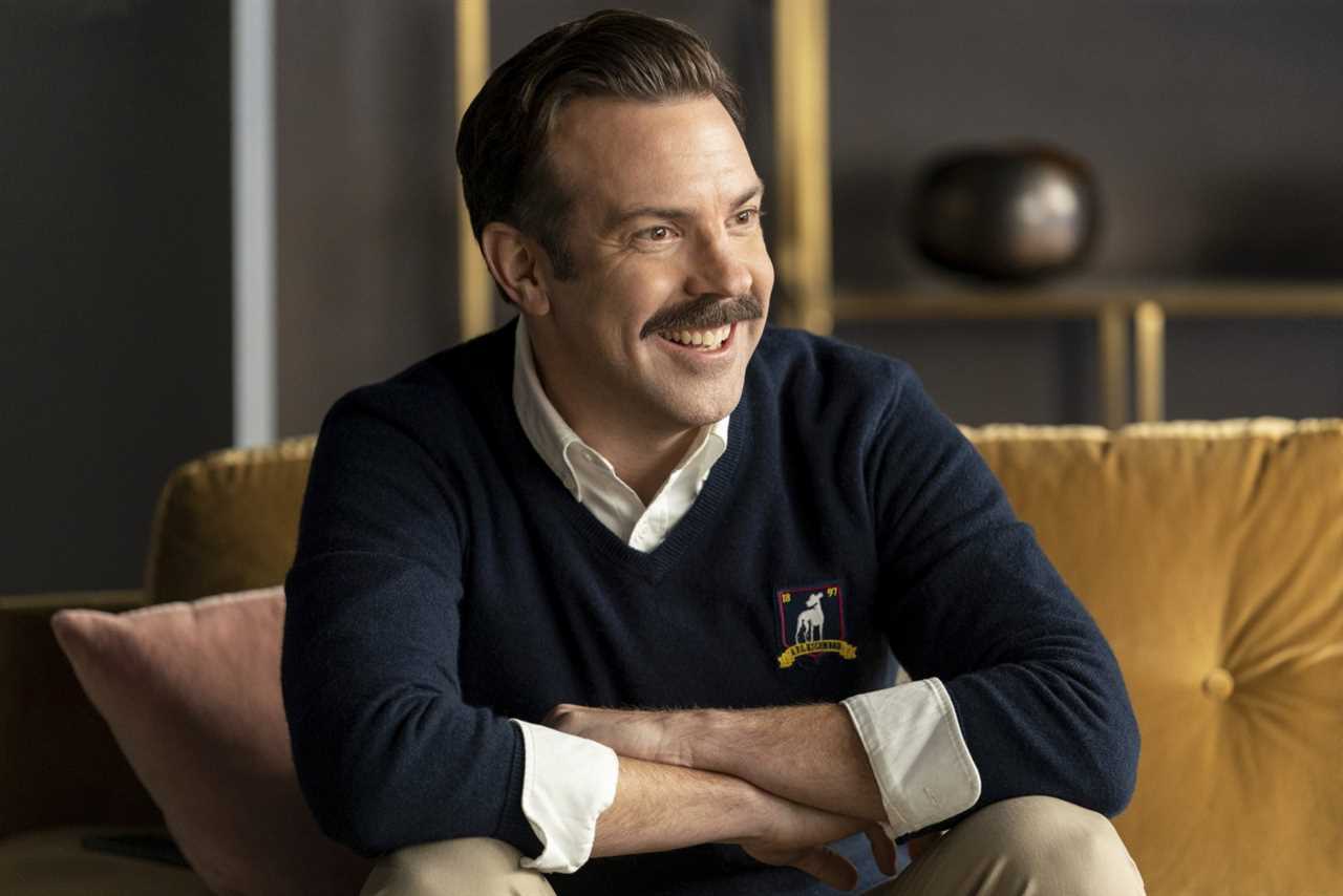 Ted Lasso sits on a couch. 