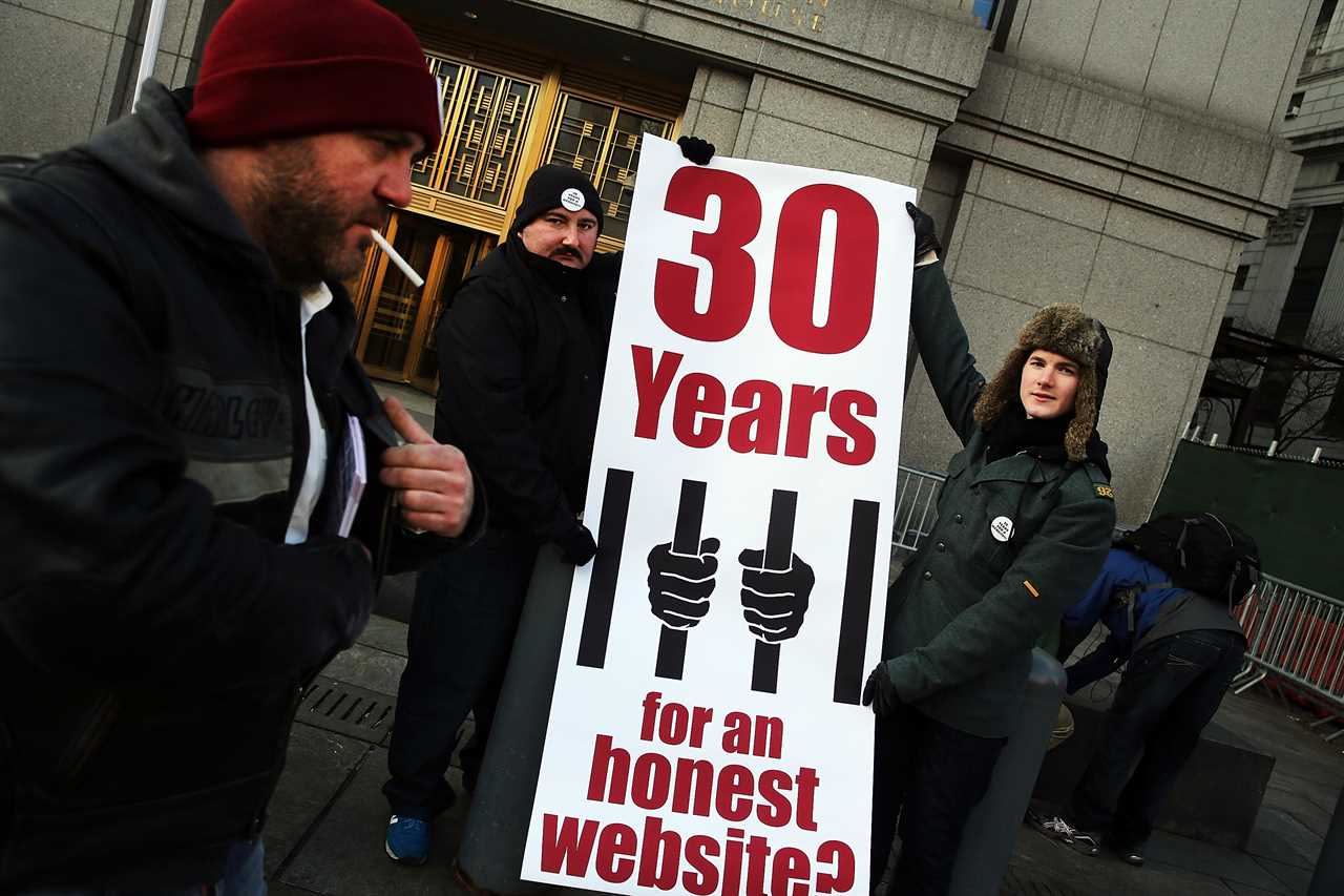 Supporters of Ross Ulbricht hold a sign reading '30 Years for an honest website?' outside a courthouse.